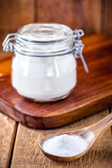 Pot of baking soda with wooden measuring spoon, chemical compound used in industry and cooking, as an antacid or as yeast