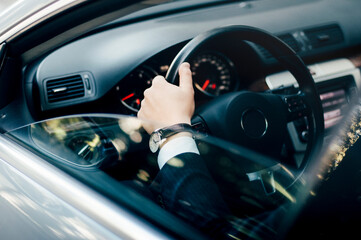 Elegant man in a suit in the showroom of his business class car.