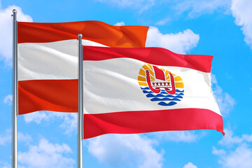 French Polynesia and Austria national flag waving in the windy deep blue sky. Diplomacy and international relations concept.