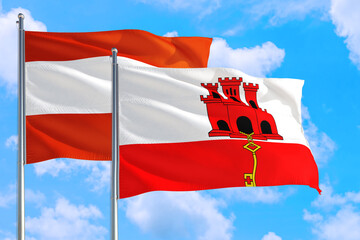 Gibraltar and Austria national flag waving in the windy deep blue sky. Diplomacy and international relations concept.