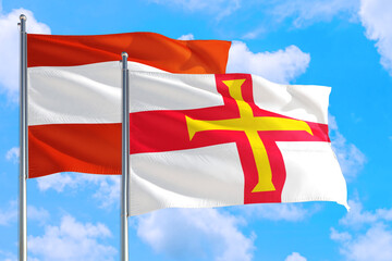 Guernsey and Austria national flag waving in the windy deep blue sky. Diplomacy and international relations concept.