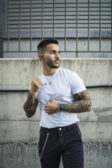 Hot tattooed man wearing a white T-shirt and black joggers