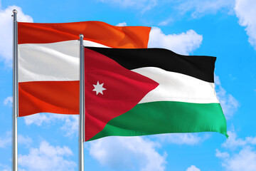 Fototapeta na wymiar Jordan and Austria national flag waving in the windy deep blue sky. Diplomacy and international relations concept.
