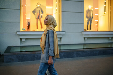 Arab girl in hijab looking on showcase in downtown