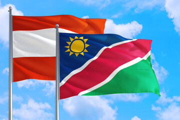Fototapeta na wymiar Namibia and Austria national flag waving in the windy deep blue sky. Diplomacy and international relations concept.