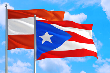 Fototapeta na wymiar Puerto Rico and Austria national flag waving in the windy deep blue sky. Diplomacy and international relations concept.