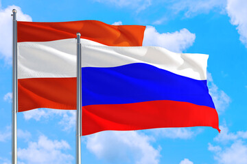 Russia and Austria national flag waving in the windy deep blue sky. Diplomacy and international relations concept.