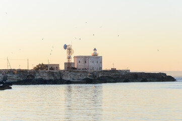 Fototapeta premium Backlit light house at sunrise time at Cala Azzurra, Favignana, Italy
