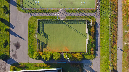 Top view of an empty small soccer sports stadium without markings. With green lawn and wooden walls