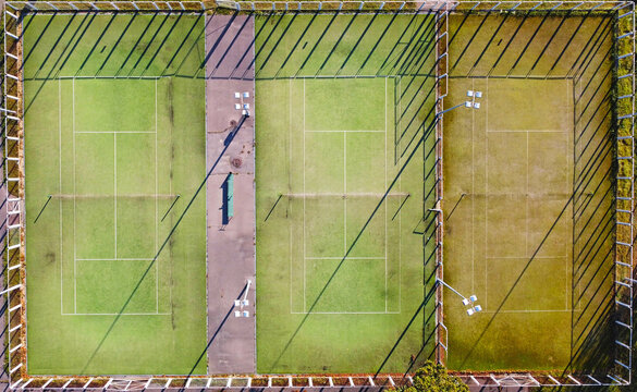 Top view of empty tennis courts with green lawn