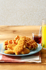 chicken tenders with waffles and a glass of orange juice