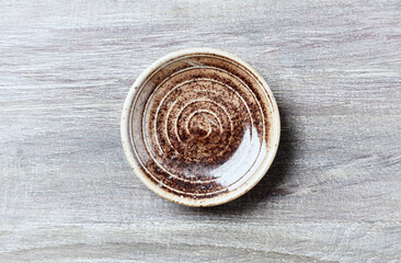 Empty ceramics plate on bright wooden background. Top view. Copy space.