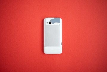 Old, outdated and worn cell phone on a red background.