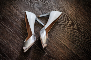 Silver shoes of the bride on the wooden floor.