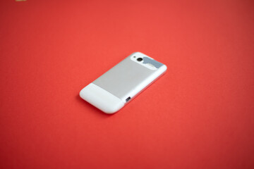 Old, outdated and worn cell phone on a red background.