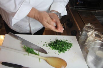 Cuoco taglia prezzemolo su tagliere con coltello. Cucina professionale