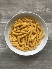 A bowl of tortiglioni pasta against a wooden background 