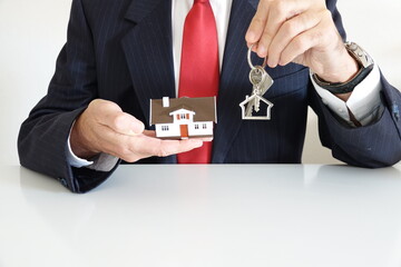 homme costume cravate rouge clés et maison dans mains