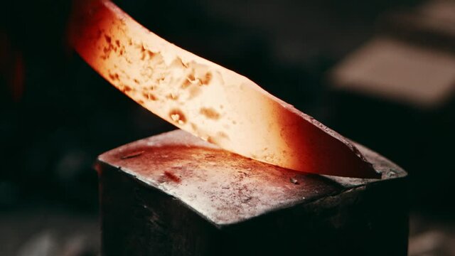 Red hot metal piece hammered on a square anvil