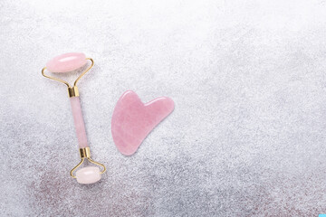 Gua Sha massager and face roller on stone background. Massage tool for facial skin care, SPA beauty treatment concept. Horizontal banner