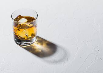 Glass with ice cubes of single malt whiskey on white background.