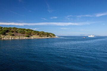 Agios Nikolaus coastline on a sunny day with clear turquoise sea and cliffs. Crete, Greece, Aegean Sea.