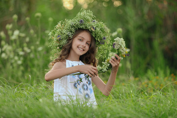 Cute little girl wearing wreath made of beautiful flowers in field