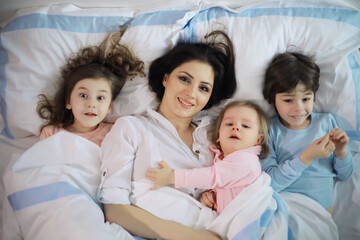 A family with children having fun on the bed under the covers during the Christmas holidays.