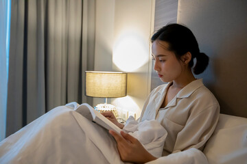 Asian women reading a book and smiling and happy Relaxing in the bedroom at home