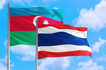 Thailand and Azerbaijan national flag waving in the windy deep blue sky. Diplomacy and international relations concept.