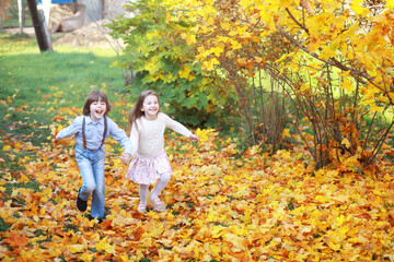 Fototapeta premium Young family on a walk in the autumn park on a sunny day. Happiness to be together.