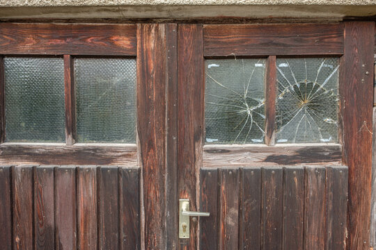 Wooden door with broken window glass