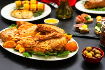 Baked chicken garnished with bay leaves and oranges. Oven-cooked poultry meat. Fried half of carcass lies on a served table