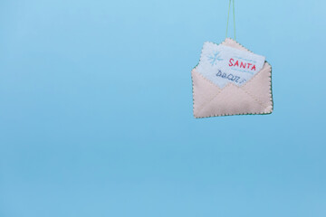 Handmade ornament shaped letter to santa clause is on a blue background. The concept of a creative...