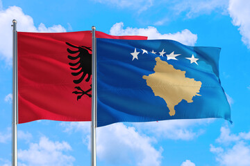 Kosovo and Albania national flag waving in the windy deep blue sky. Diplomacy and international relations concept.
