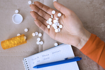 Womans hand with pills lying on couch with death note close-up. Increase in number of suicides concept