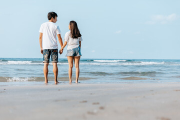 Romantic couple holding hands and stand together on beach. Man and woman in love.