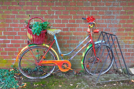 Old brightly painted bicycle on the side of the road.