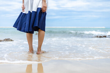 Woman barefoot walking on summer along wave of sea water and sand on the beach.