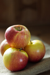 Stack of four red organic apples on brown background