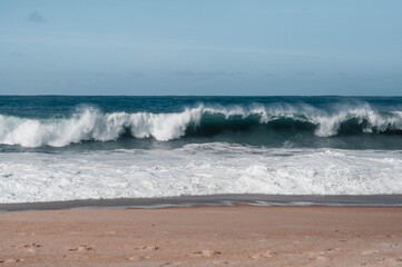 Fototapeta na wymiar Blue waves on the shore. Sunny weather. Sandy beach