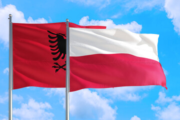 Poland and Albania national flag waving in the windy deep blue sky. Diplomacy and international relations concept.