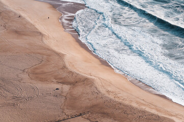 Ocean and beach view from above, shooting from above, blue waves, orange sand. Foam from waves on...