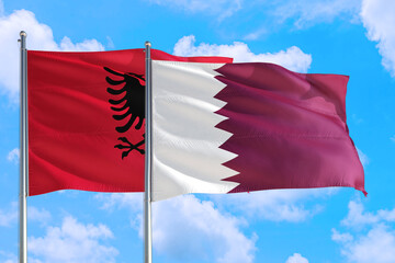 Qatar and Albania national flag waving in the windy deep blue sky. Diplomacy and international relations concept.