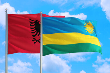 Rwanda and Albania national flag waving in the windy deep blue sky. Diplomacy and international relations concept.