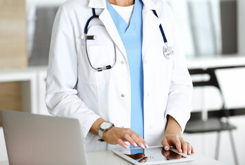 Unknown woman-doctor at work in clinic. Female physician using tablet computer, close-up. Medicine concept