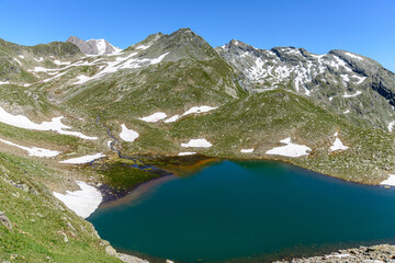 Wild lake Southtirol Italia Val pusteria Alpine pastures with a deep blue lake, green meadows and a blue sky with fleecy clouds, in summer