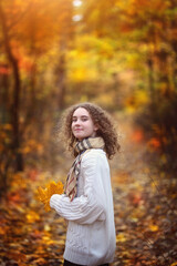 young smiling teenage girl with curly hair on an autumn day in the park