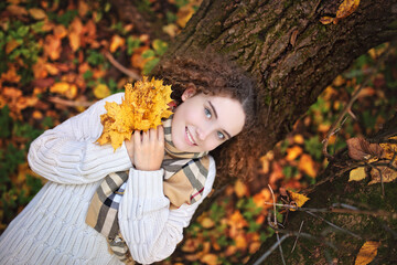 young smiling teenage girl with curly hair on an autumn day in the park