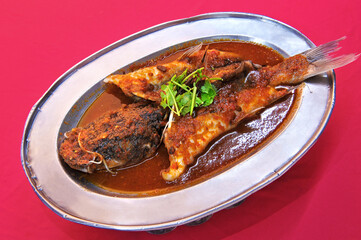 Steamed Cat fish (Pak Sou Gong or Baung) in flavorful special sauce on red table cloth background.
